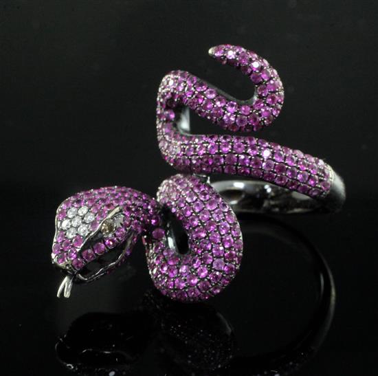 A modern blackened? gold, diamond and ruby encrusted serpent ring, size N.